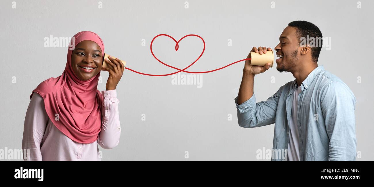 Junge schwarze muslimische Paar mit kann Telefon auf grauem Hintergrund Stockfoto