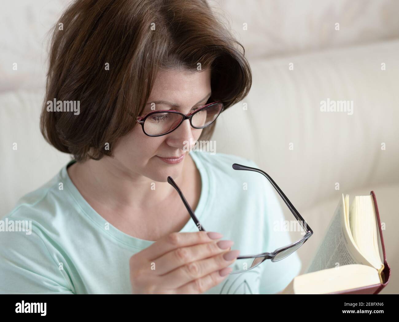 Frau mit eingeschränktem Sehvermögen lesen Buch durch zwei Gläser Stockfoto