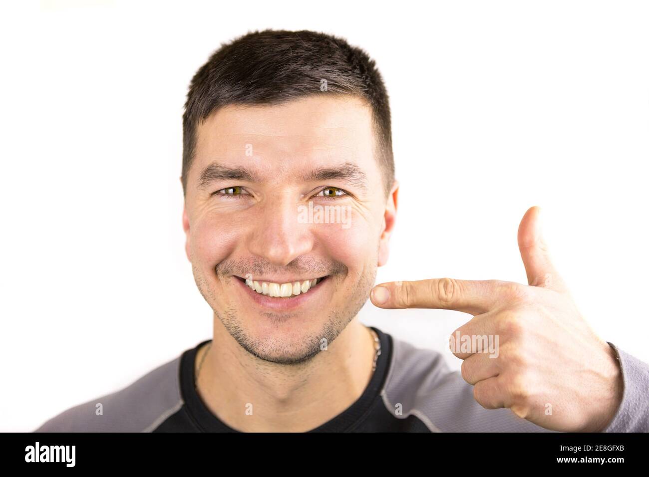 Schöne männliche schneeweiße Lächeln und Lippen des kaukasischen Aussehen Nahaufnahme. Zeigt den Finger auf die Zähne. Borsten von Stoppeln, Rasur, Brutalität. Zahnärztliche PR Stockfoto