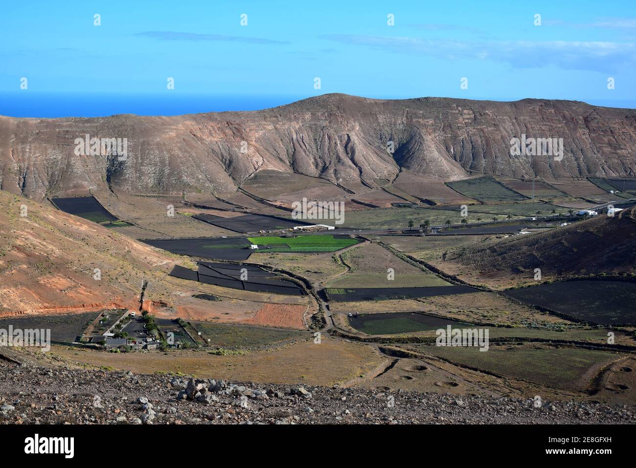 Blick auf ein Tal mit Feldern für die Landwirtschaft. Im Hintergrund die Bergkette Los Ajaches. In Der Nähe Von Femés. Lanzarote, Spanien. Stockfoto