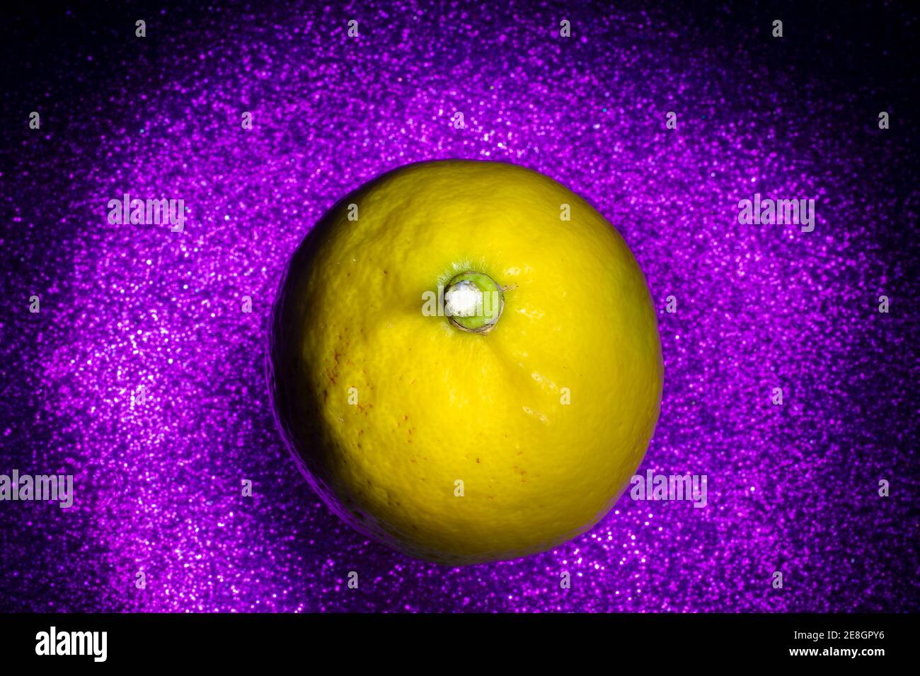 Luftaufnahme Makro Foto.frisch gepflückt Zitrone schwimmend auf lila Hintergrund. Lichtpinsel-Technik. Stockfoto