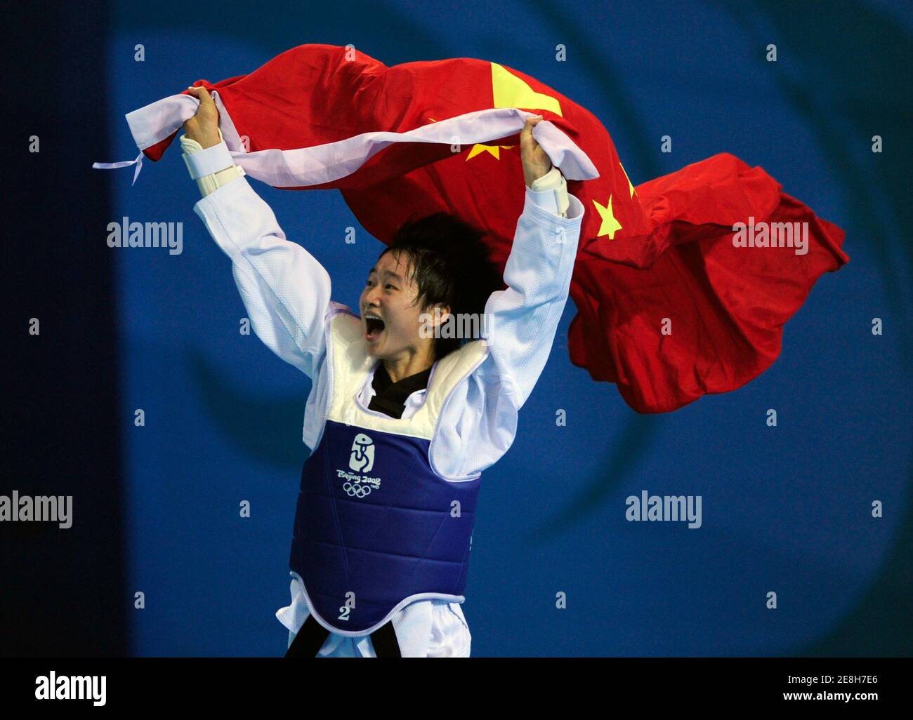 Wu Jingyu aus China läuft mit der chinesischen Flagge, als sie den Sieg über Buttree Puedpong aus Thailand während des Taekwando-Goldmedaillenwettbewerbs der Frauen bei den Olympischen Spielen 2008 in Peking am 20. August 2008 feiert. REUTERS/Desmond Boylan (CHINA) Stockfoto