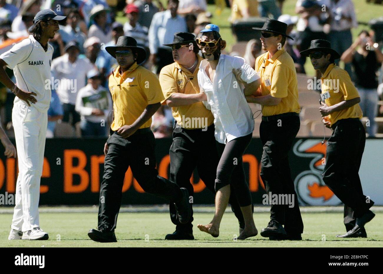 Indiens Ishant Sharma (L) Uhren Sicherheit einen Mann trägt eine Affenmaske abseits des Spielfeldes während des vierten Tages der ihre vierte und letzte Test-Cricket-Spiel gegen Australien in Adelaide Oval 27. Januar 2008 begleiten. REUTERS / Willen Burgess (Australien) Stockfoto