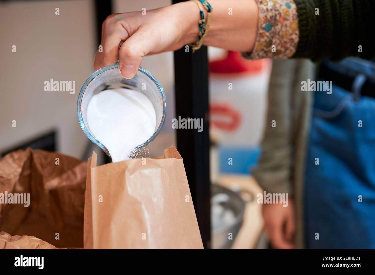 Crop anonyme Verkäuferin Gießen Waschpulver nach Gewicht aus Becher in Papierpaket, während die Bestellung für den Kunden in Großladen Stockfoto