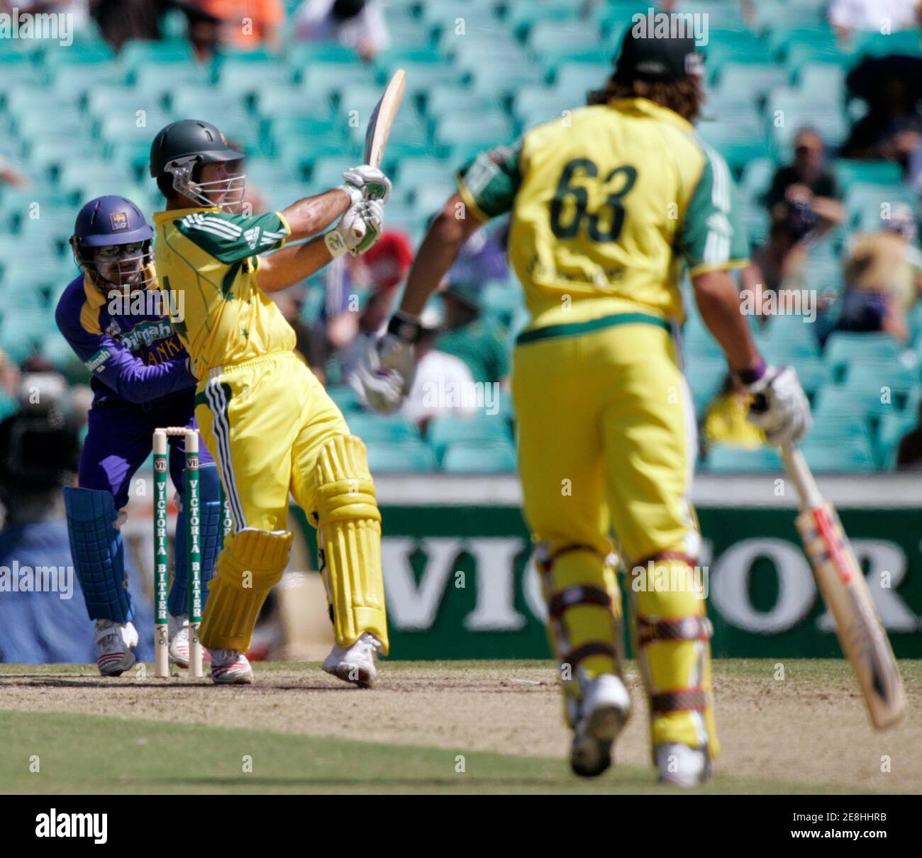 Australiens Kricket Kapitän Ricky Ponting (2. L) trifft eine sechs, als sein Andrew Symonds (R) Teamkollege und Sri Lanka Wicketkeeper Kumar Sangakkara Blick auf während ihrer zweiten begrenzte Overs eintägigen final Cricket-Match in Sydney 12. Februar 2006. Sri Lanka führen 1: 0. REUTERS / Willen Burgess Stockfoto