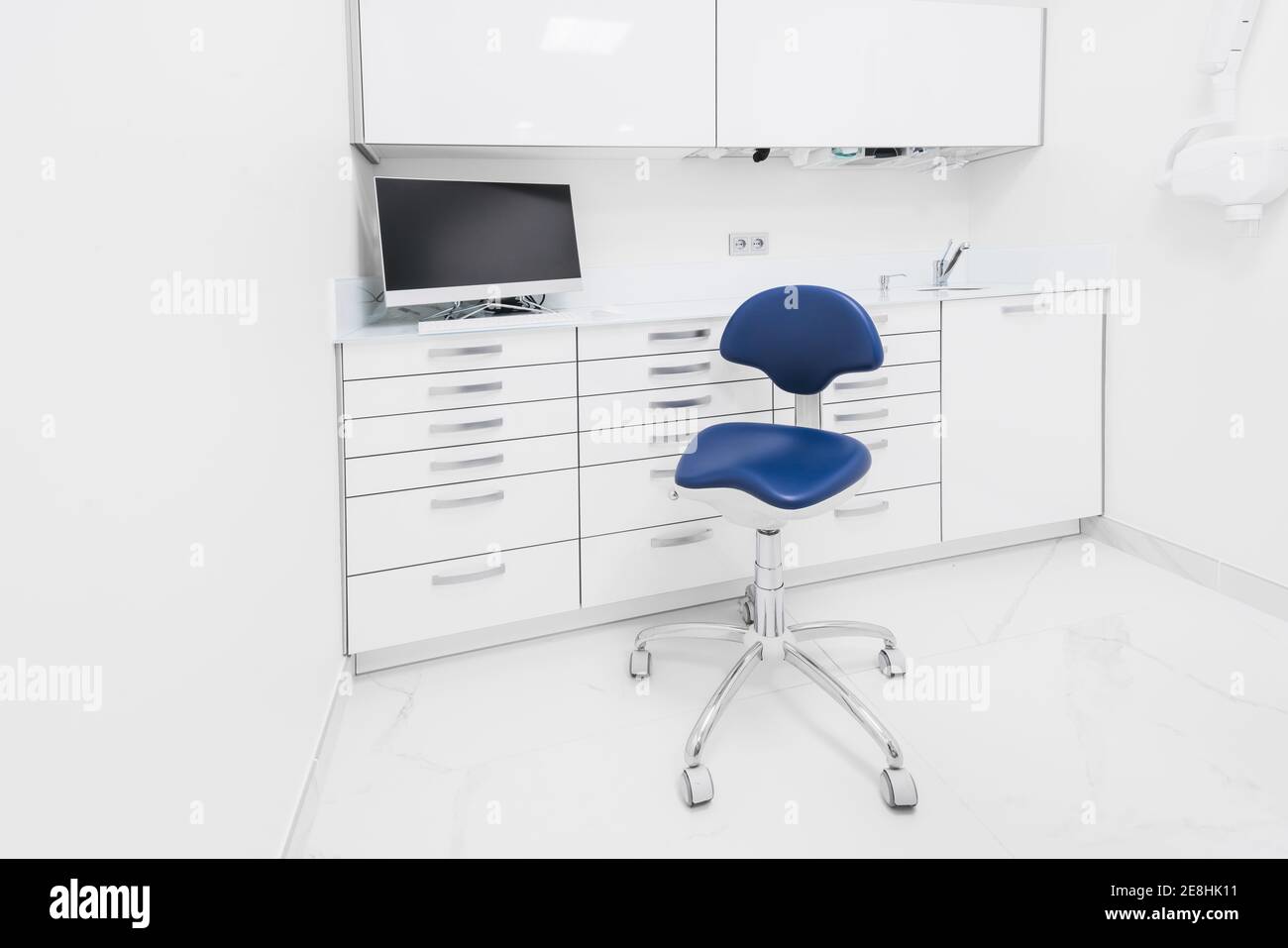 Stilvolles Innenraumdesign des modernen hellen Klinikraumes mit Weiß Möbel und blauer Stuhl Stockfoto