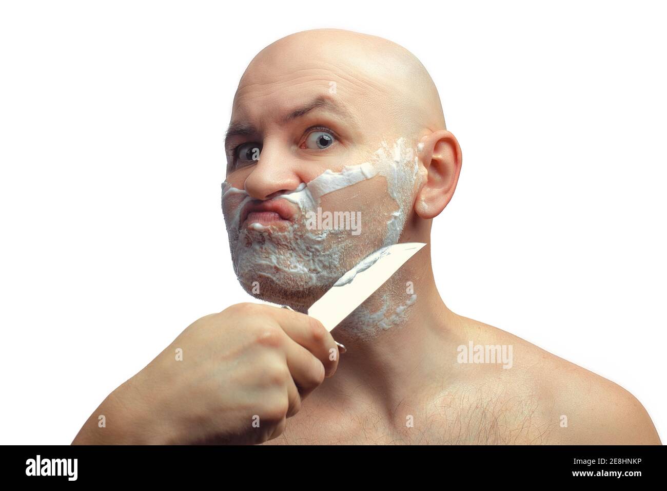 Ein kahlköpfiger weißer Mann rasiert seine Stoppeln mit einem glänzenden Küchenmesser. Ein Männergesicht mit Rasierschaum. Stockfoto