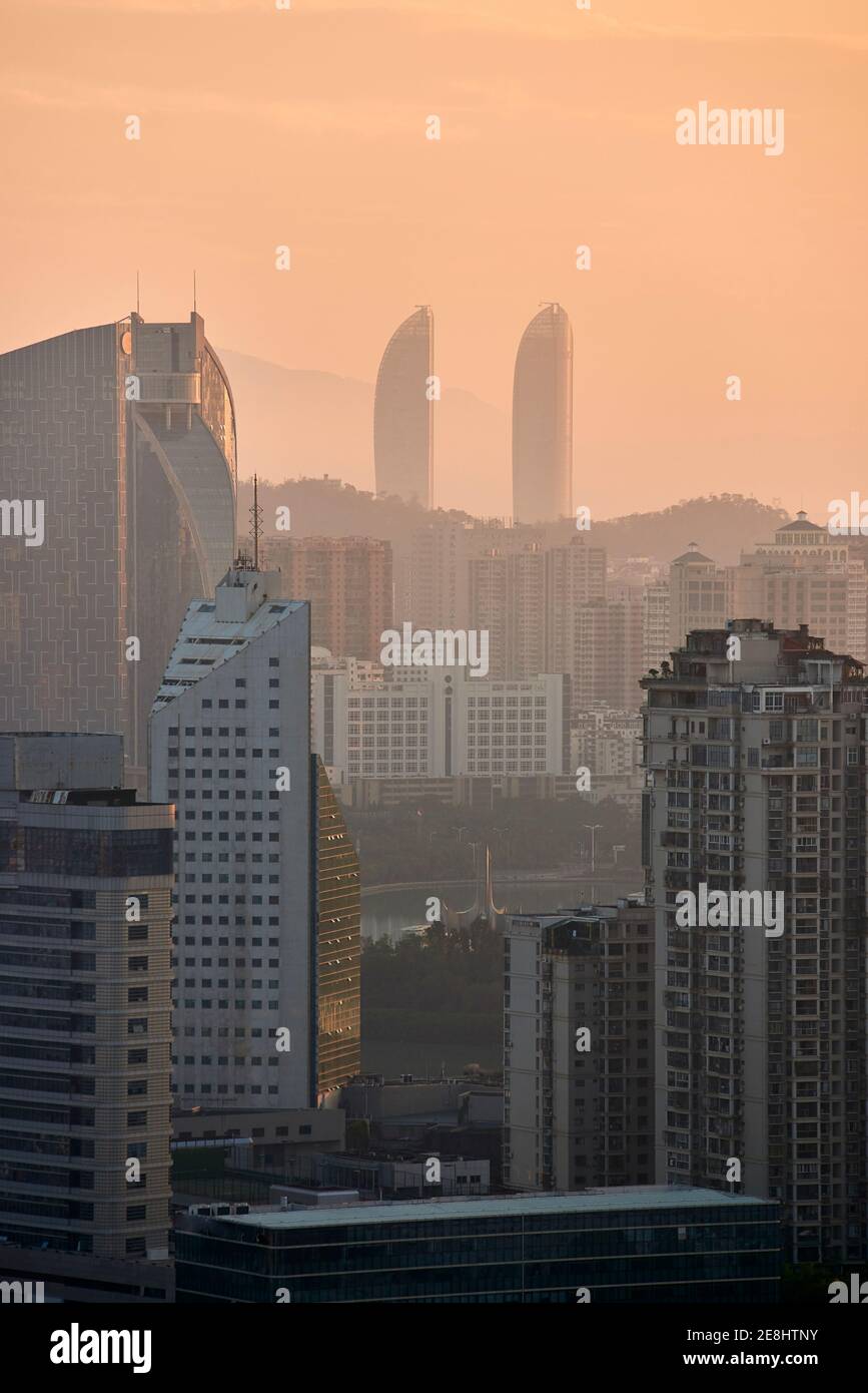 Friedlicher Blick auf die moderne Metropole mit Wolkenkratzern und Wohngebäuden Unter orangefarbenem Himmel in der Dämmerung Stockfoto
