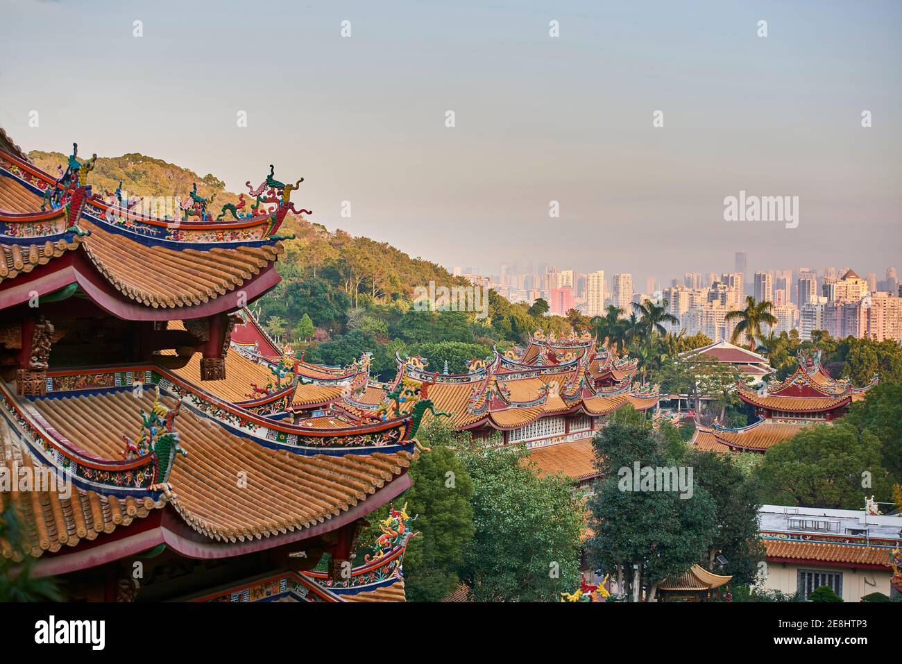 Authentischer buddhistischer Tempel gegenüber modernen mehrstöckigen Wohngebäuden in Moderne Stadt in der Abendsonne Stockfoto
