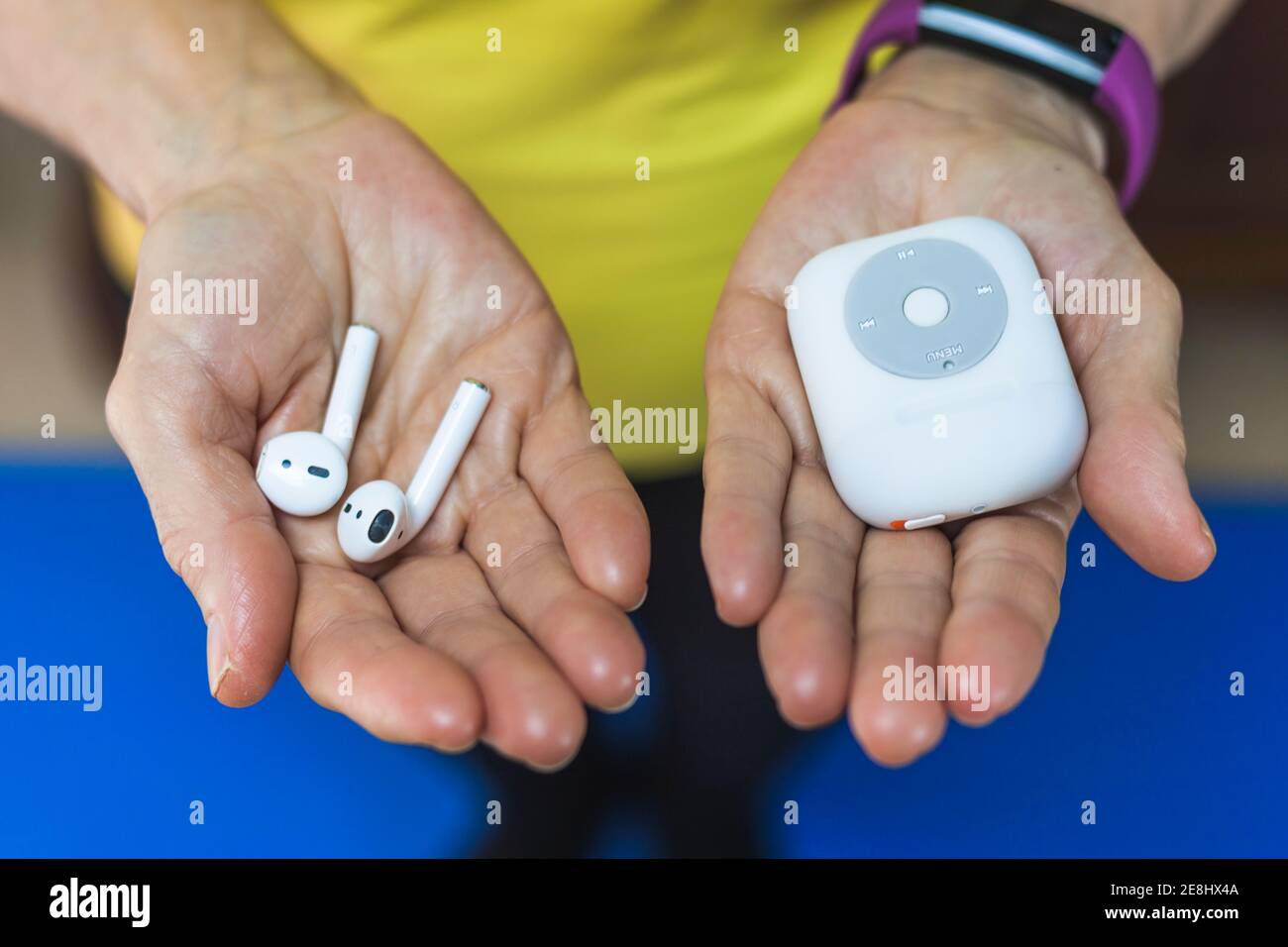 Von oben Crop nicht erkennbare Person trägt Fitness Armband zeigt drahtlos Ohrstöpsel und moderner MP3-Player an den Händen Stockfoto
