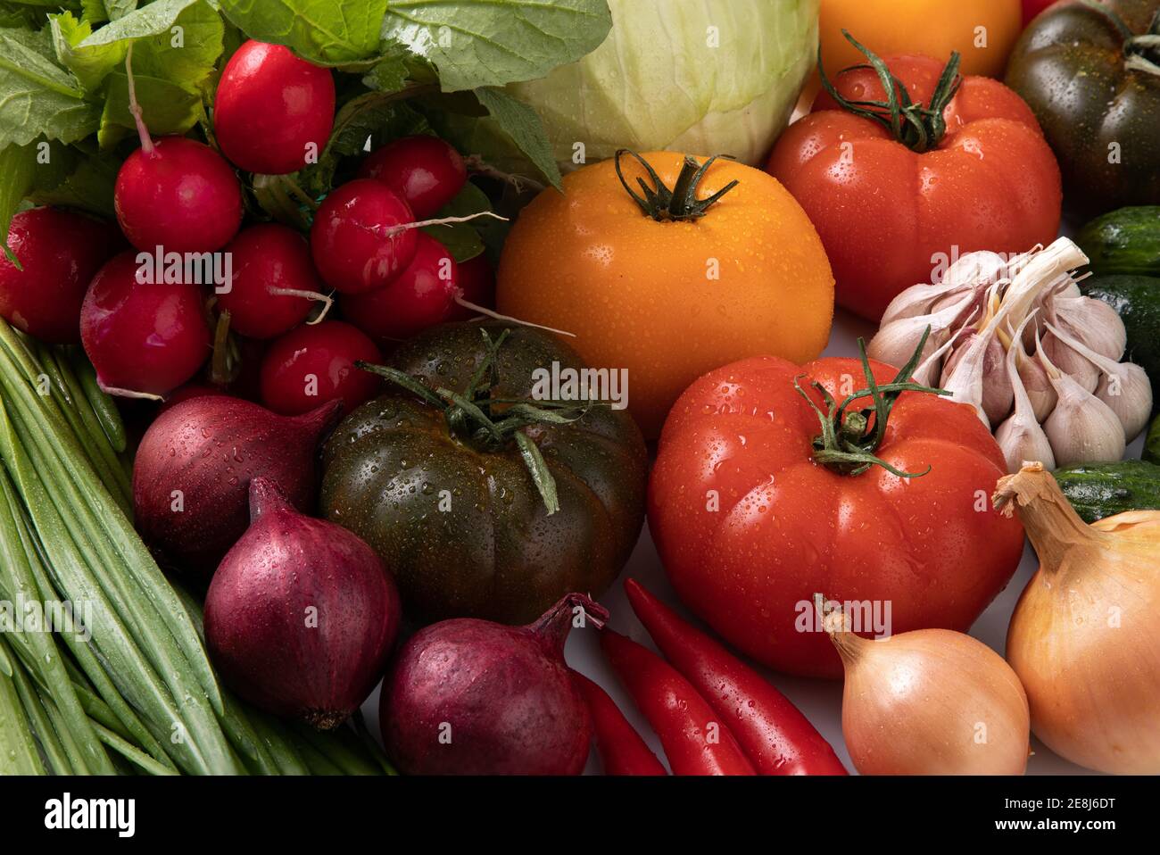 Frisches Gemüse mit Wassertropfen, Tomaten, Zwiebeln, Rettich Stockfoto