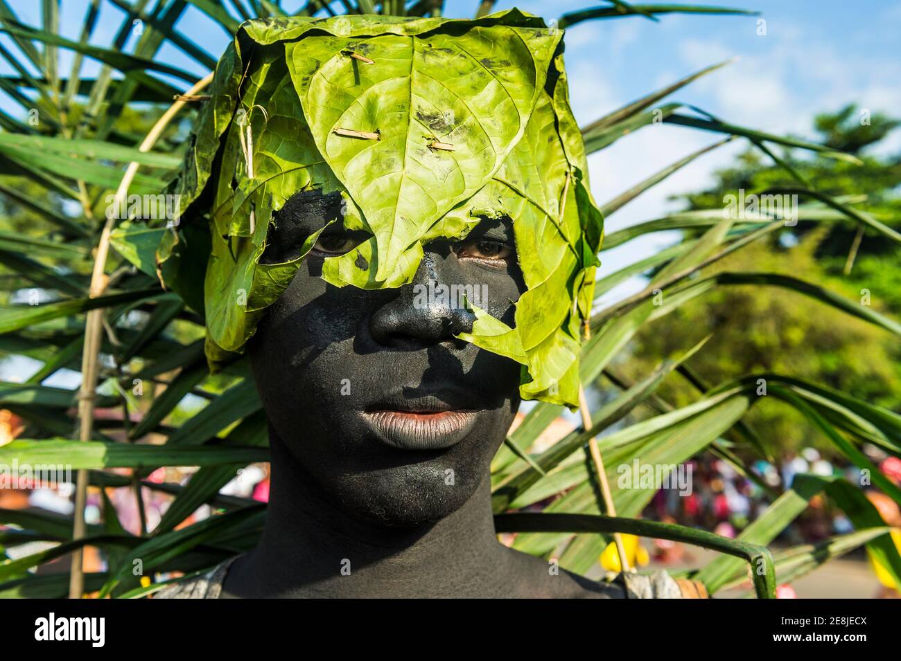 Grimmig aussehender Mann mit einem Bananenblatt über dem Kopf, Karneval in der Stadt Sao Tome, Sao Tome und Principe, Atlantik Stockfoto