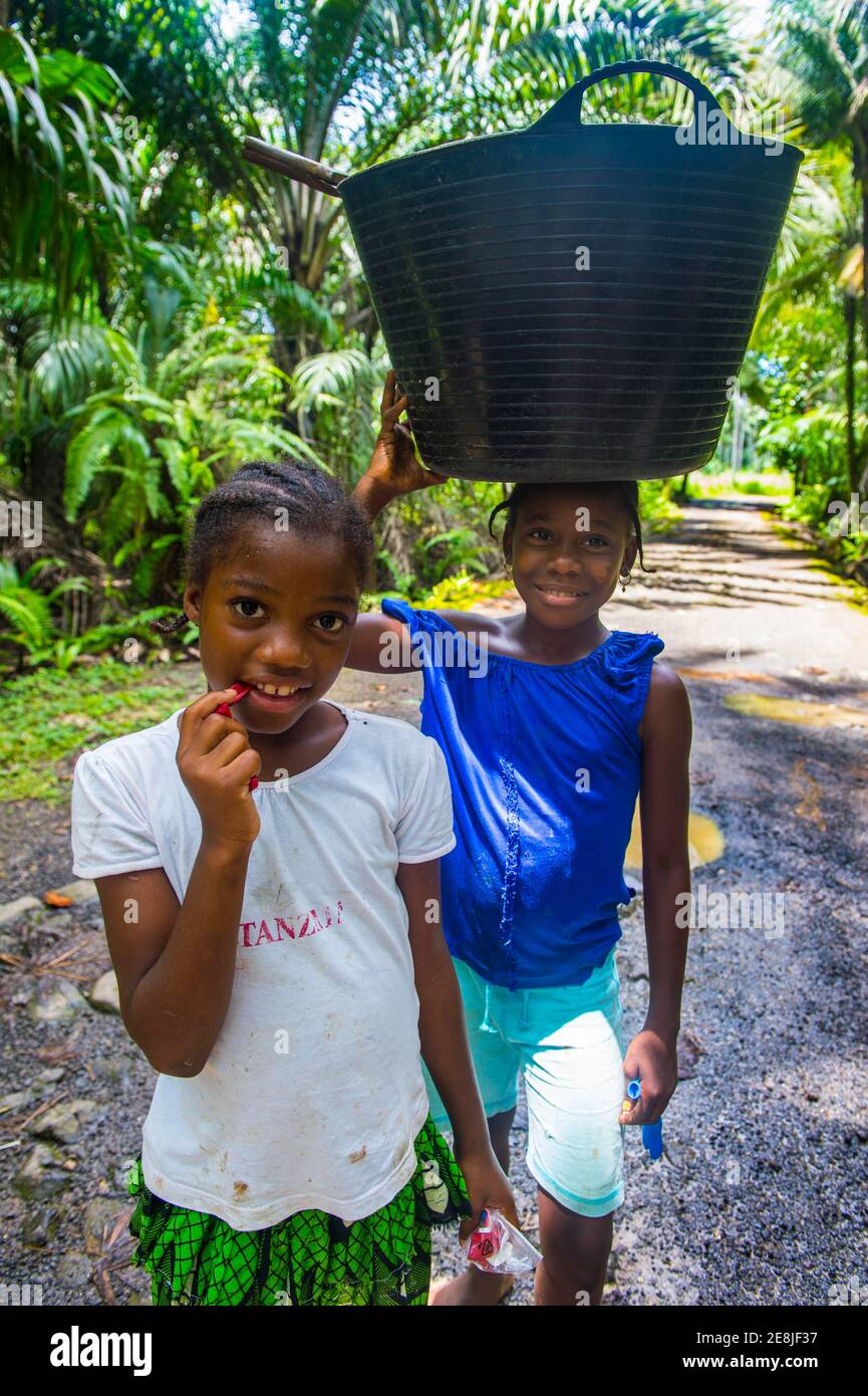 Kinder mit Eimern auf dem Kopf durch den Dschungel der Südküste von Sao Tome, Sao Tome und Principe, Atlantik Stockfoto