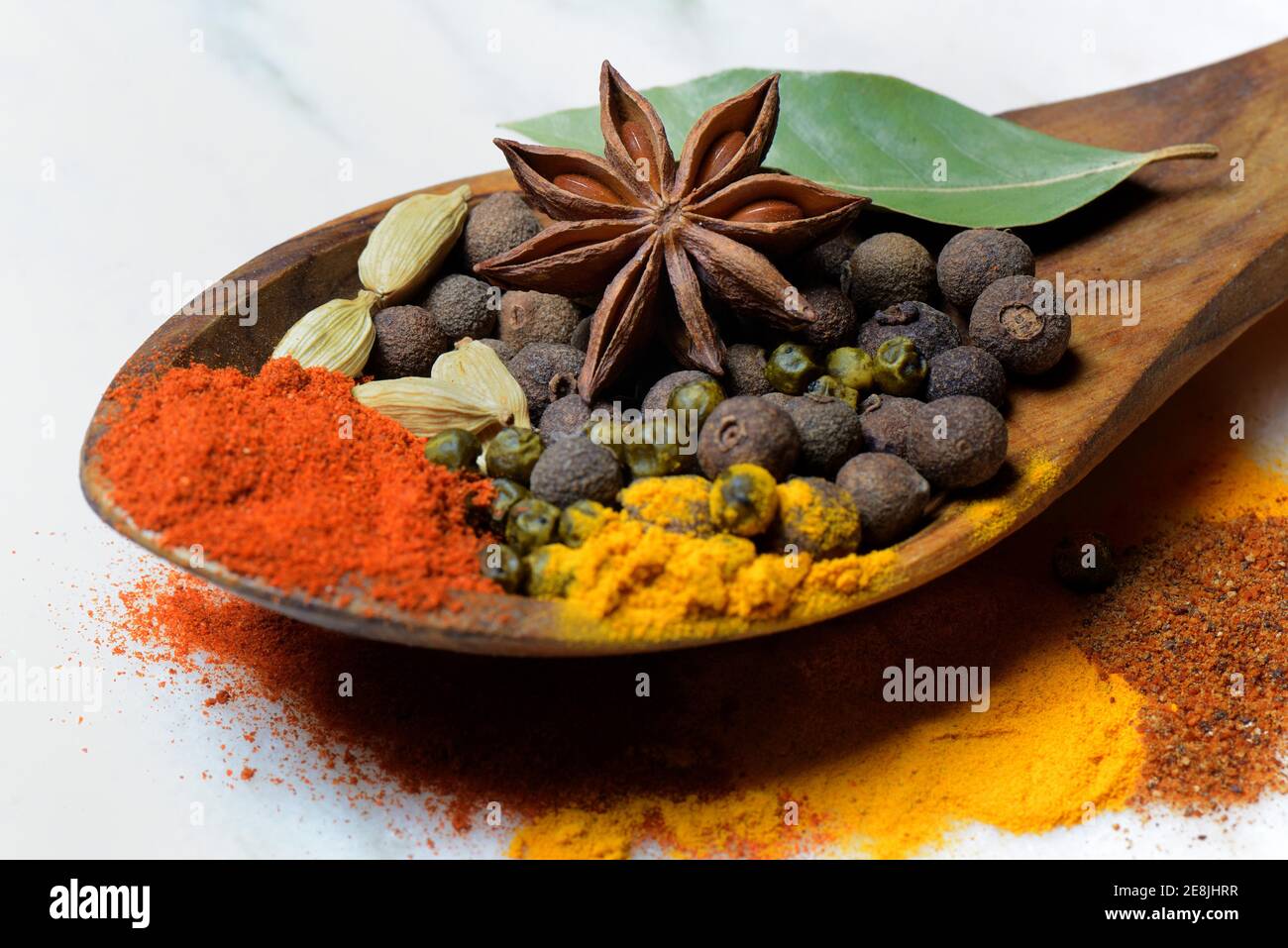 Verschiedene Gewürze in Holzlöffel, Paprika, Chili, Piment, Kurkuma, Sternanis, Kardamom, grüner Pfeffer, Muskatpulver, Lorbeerblatt Stockfoto