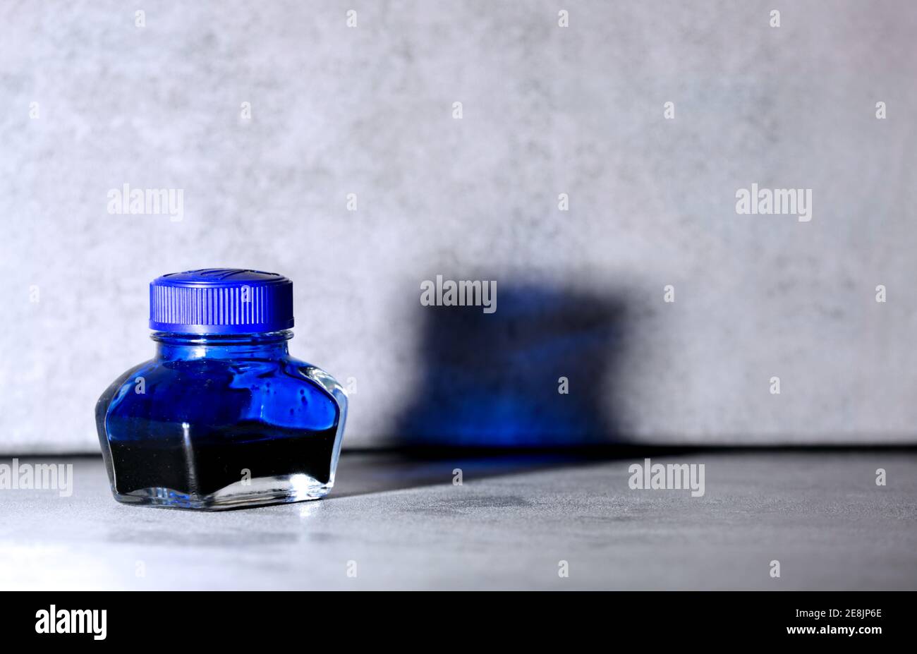 Nicht volle blaue Tintenflasche mit grauem Hintergrund Stockfoto