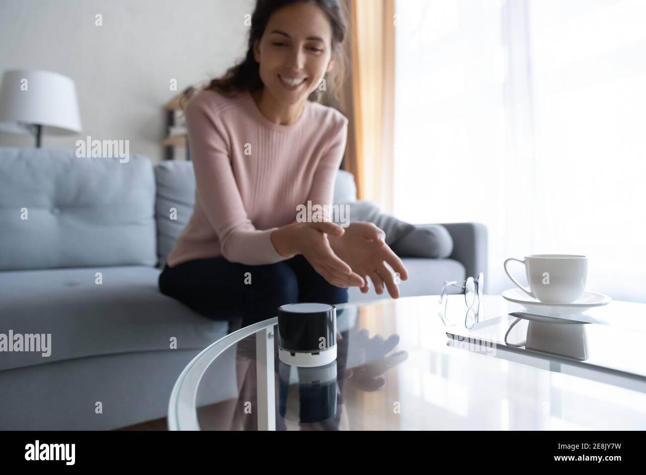 Glückliche junge Frau mit drahtlosen Sprachassistenten. Stockfoto