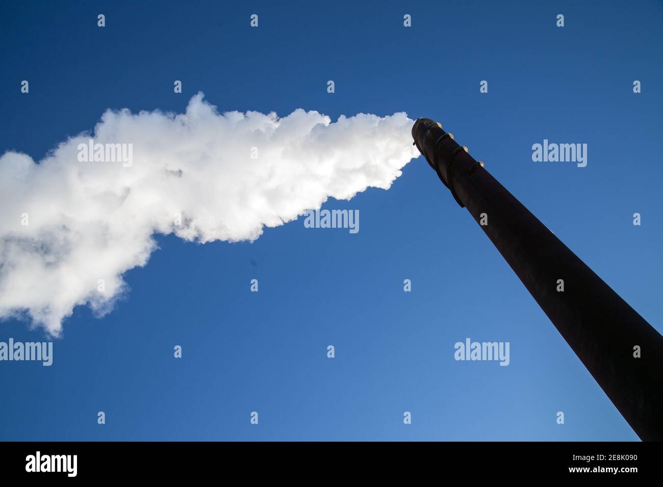 Eine lange Wolke aus weißem Rauch, die aus einem metallischen Kamin gegen einen tiefblauen Himmel entweicht. Foto Bo Arrhed Stockfoto