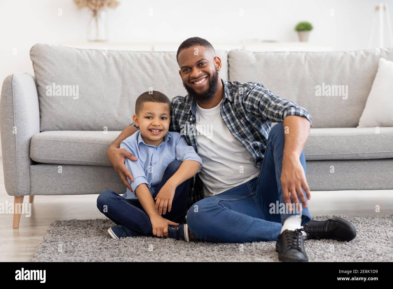 Afrikanischer Vater Und Sohn Umarmen Sitzen Auf Dem Boden Zu Hause Stockfoto