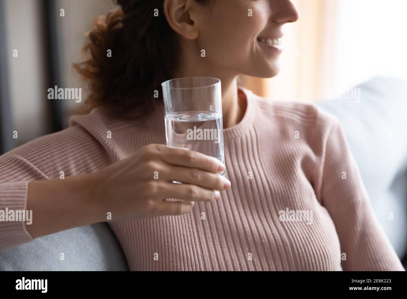 Nahaufnahme verträumte junge Frau hält Glas reines Wasser. Stockfoto