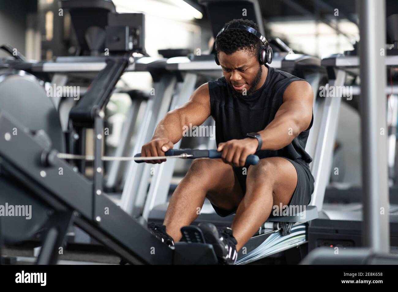 Motivierter schwarzer Sportler beim Training auf dem Rudergerät Stockfoto