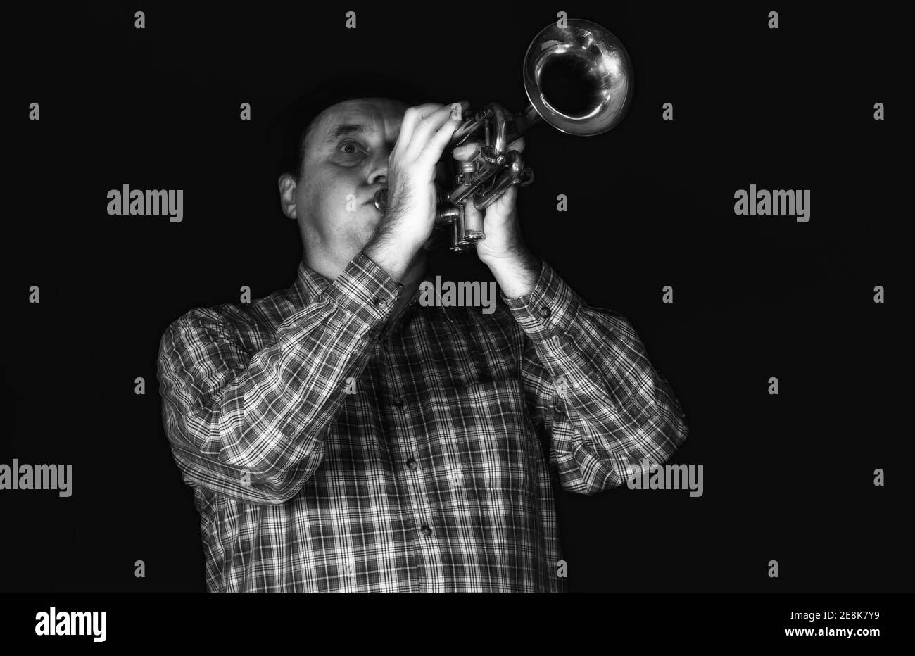 Schwarz-Weiß-Porträt eines reifen Trompeters, der das Instrument auf einer Bühne spielt. Stockfoto
