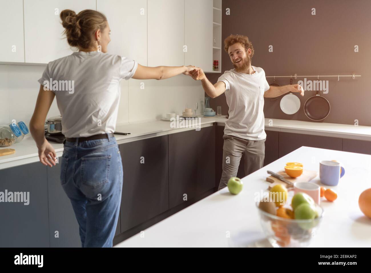 Waltzing in einem neuen Zuhause junges Paar tanzen feiert ihren neuen Kauf des eigenen Hauses zu kaufen. Glückliche neue Familie in der Küche tragen lässig Stockfoto