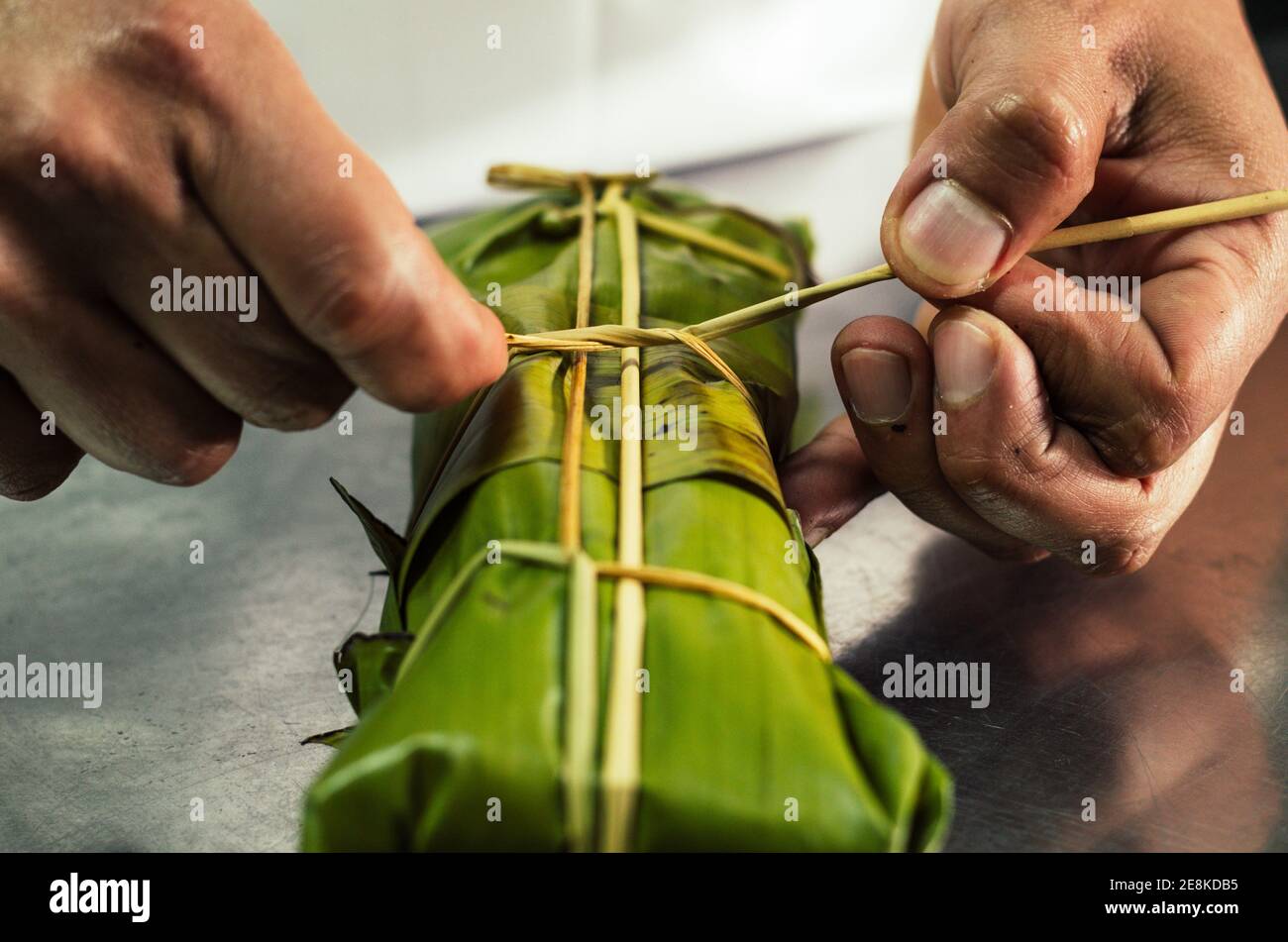 Peruanische Hände binden eine traditionelle Tamale mit Bananenblättern Stockfoto