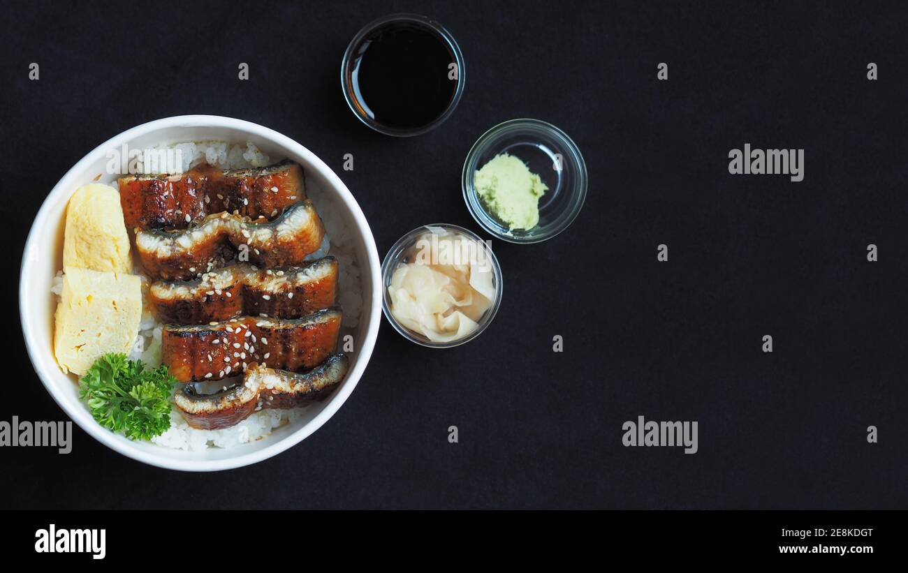 Draufsicht und Fokus auf Unadon oder unagi Donburi oder Aal Schüssel ist ein Gericht mit Ursprung in Japan auf schwarzem Hintergrund. Stockfoto