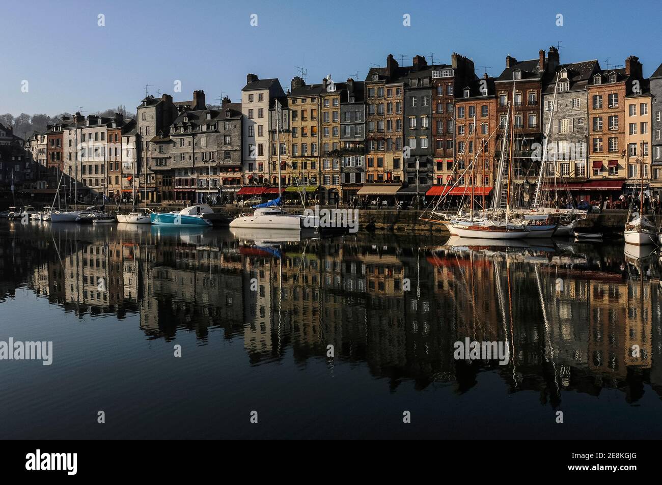 Hohe, schmale Häuser aus dem 17. Und 18. Jahrhundert säumen den beliebten und malerischen Quai Sainte Catherine werden im Januar mit festgetäuten Yachten und anderen Vergnügungsbooten in den ruhigen Gewässern des Vieux Bassin (Old Basin oder Dock), Brennpunkt der historischen Honfleur, Calvados, Normandie, Frankreich reflektiert. Die meisten Häuser haben zwei Besitzer, mit ihren nach hinten gerichteten oberen Etagen mit Blick auf die Straßen hinter dem Hafen. Stockfoto