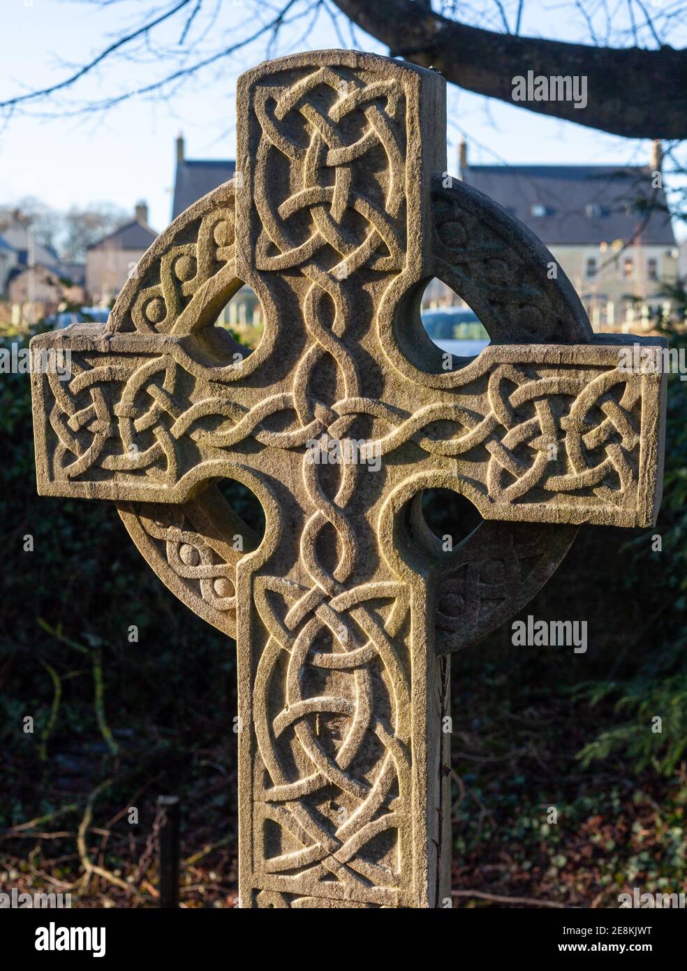 Sonnenbeschienene tief geschnitzte Grabmarke aus Stein mit keltischem Kreuz Design auf einem Friedhof in Yorkshire Stockfoto