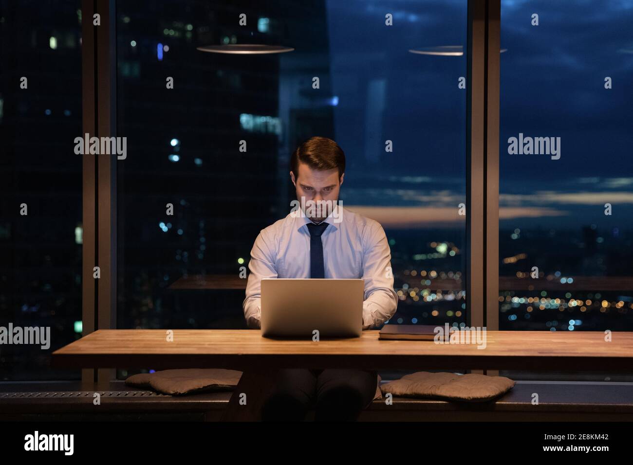 Fokussierter männlicher Mitarbeiter entwickelt Projekt von Laptop spät am Abend Stockfoto