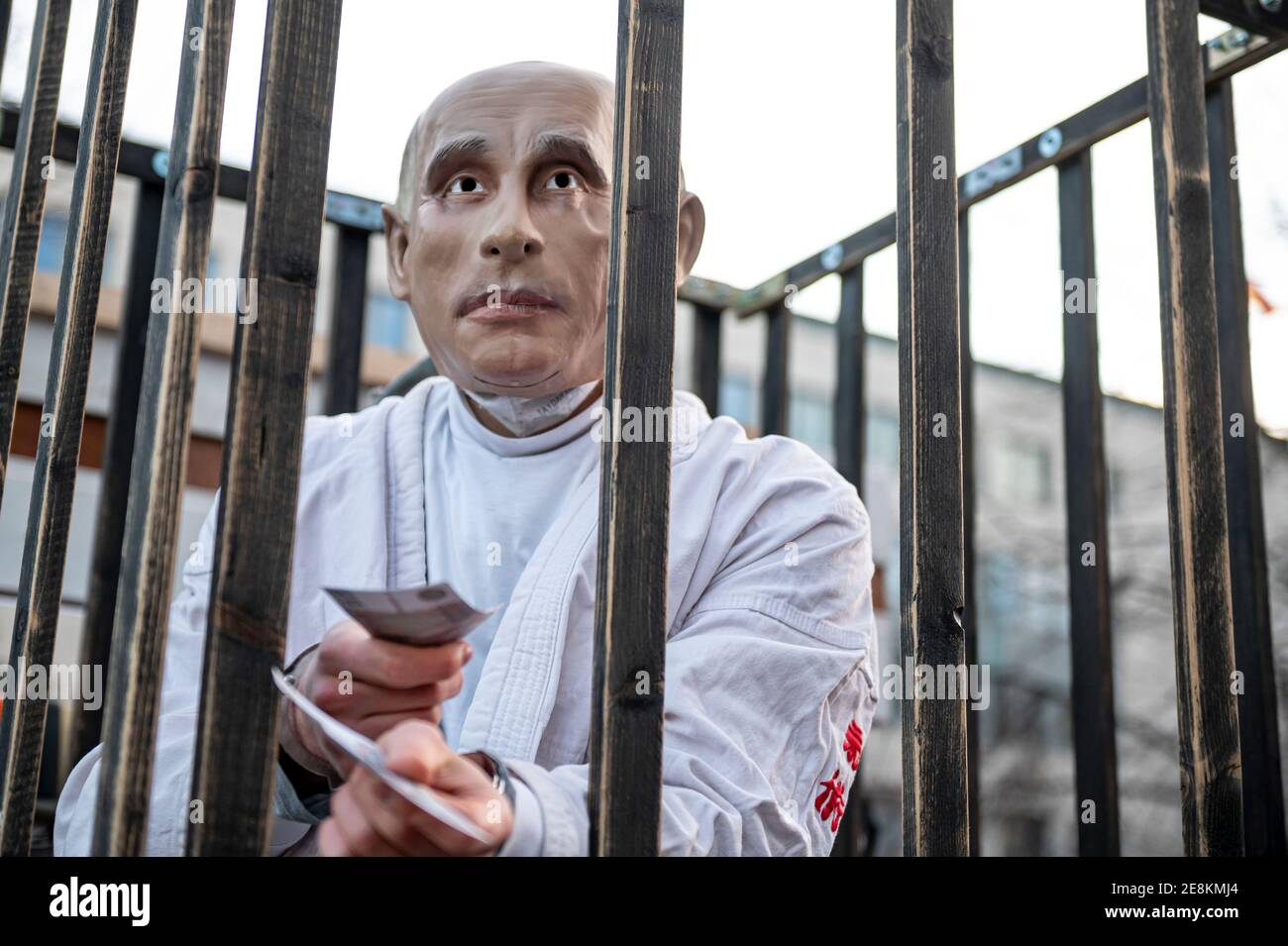 Berlin, Deutschland. Januar 2021. Eine Person, die eine Putin-Maske trägt, steht in einem Holzkäfig auf Den Hag und verteilt bei einer Demonstration, die zur Freilassung der russischen Oppositionsfigur Nawalny aufruft, gefälschte Banknoten. Quelle: Fabian Sommer/dpa/Alamy Live News Stockfoto