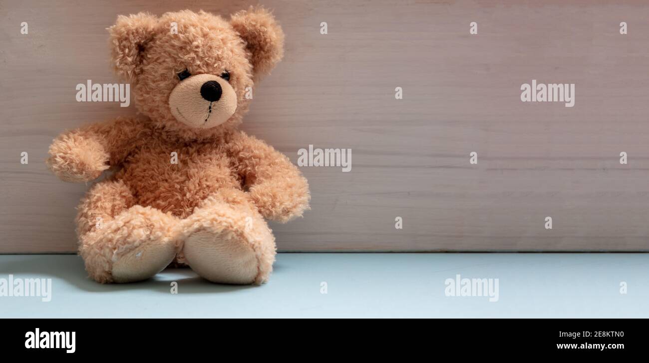 Teddybär sitzt in einem leeren Raum, pastellblauer Boden, weiße Holz Wand Hintergrund, Kind allein im Kinderzimmer Konzept Stockfoto