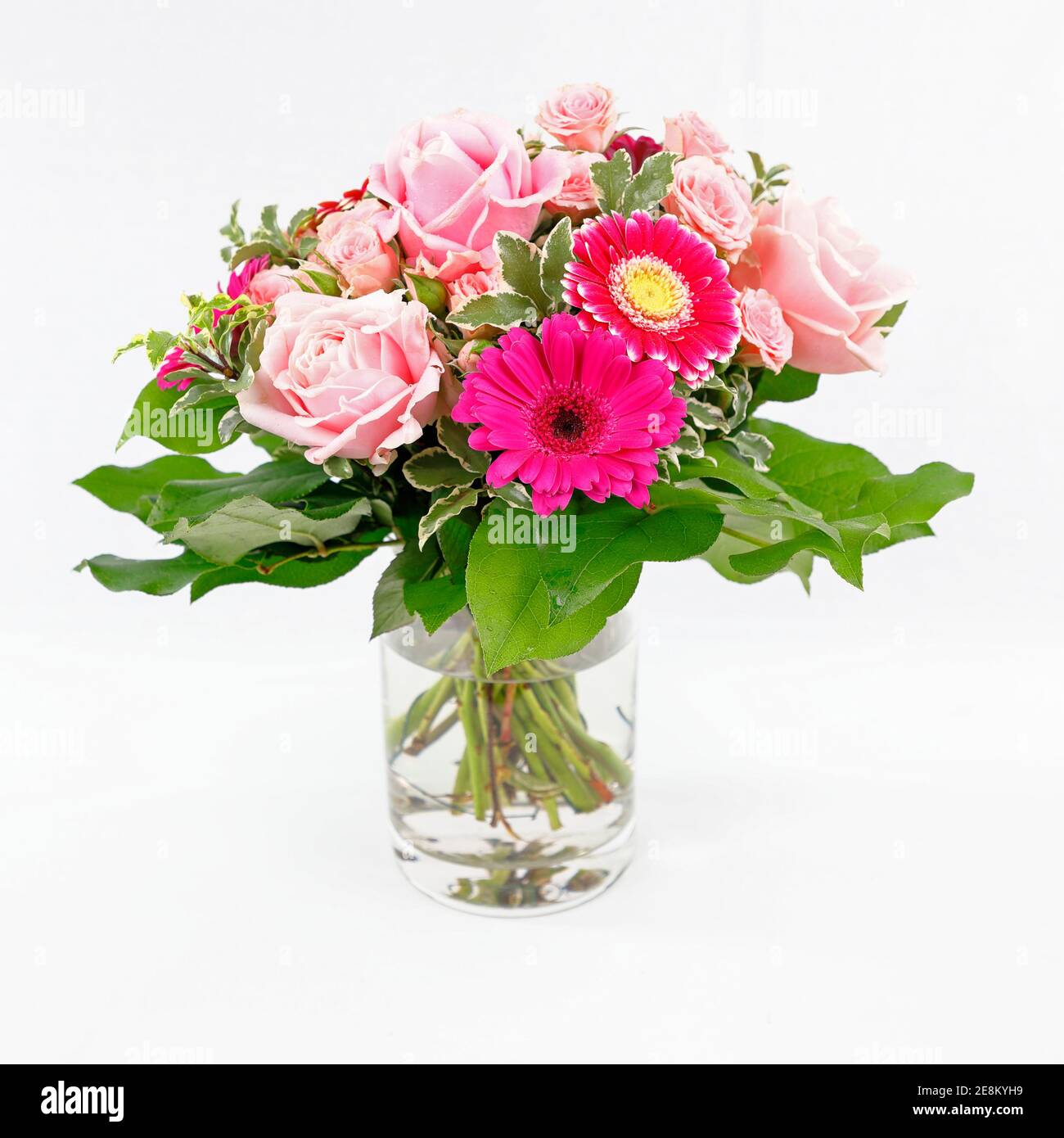 Ein hübscher Strauß Rosen und Gerberas in einer Glasvase, isoliert auf weißem Grund Stockfoto