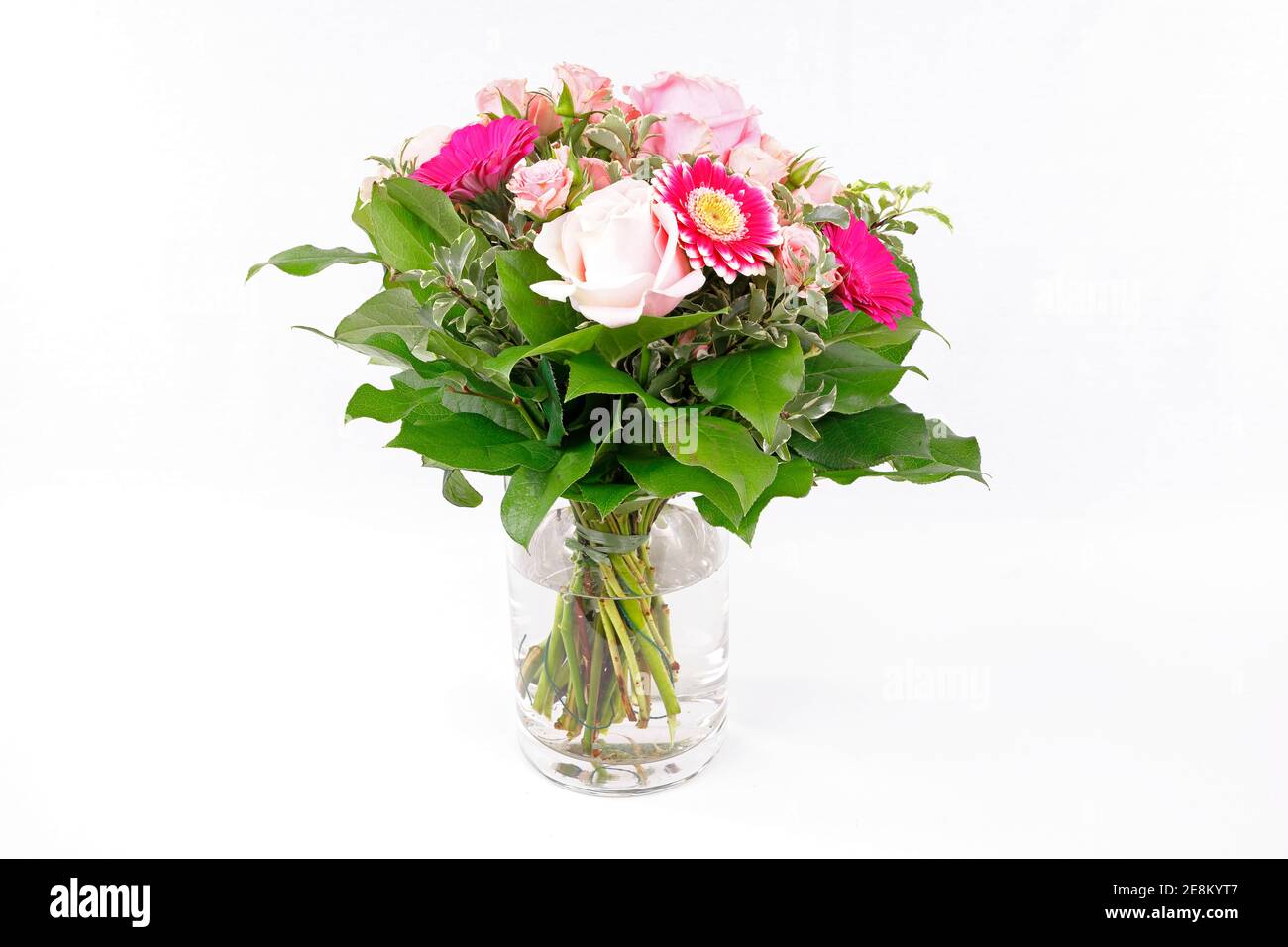 Ein hübscher Strauß Rosen und Gerberas in einer Glasvase, isoliert auf weißem Grund Stockfoto
