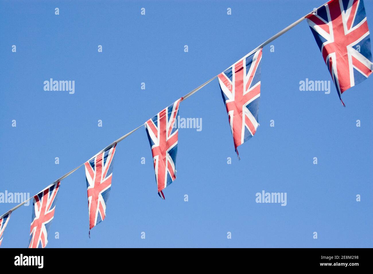 Bunting, das aus der Unionsflagge des Vereinigten Königreichs besteht, die gegen einen blauen Himmel fliegt. Stockfoto