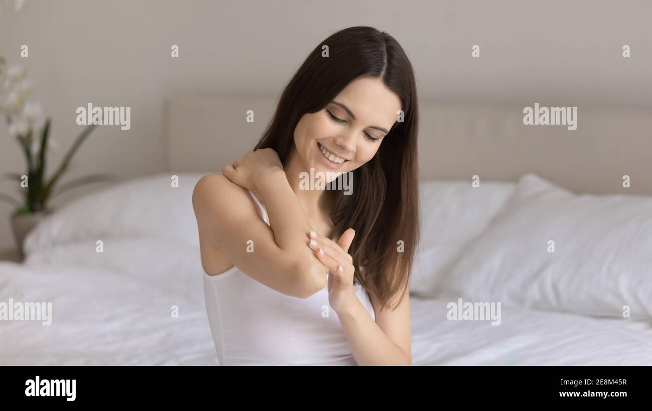 Lächelnde junge Frau Creme auf die Handhaut auftragen Stockfoto