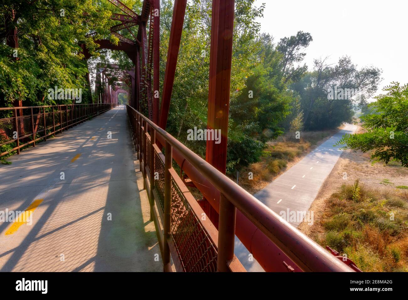 Fahrradbrücke führt über einen weiteren Radweg durch Bäume Stockfoto