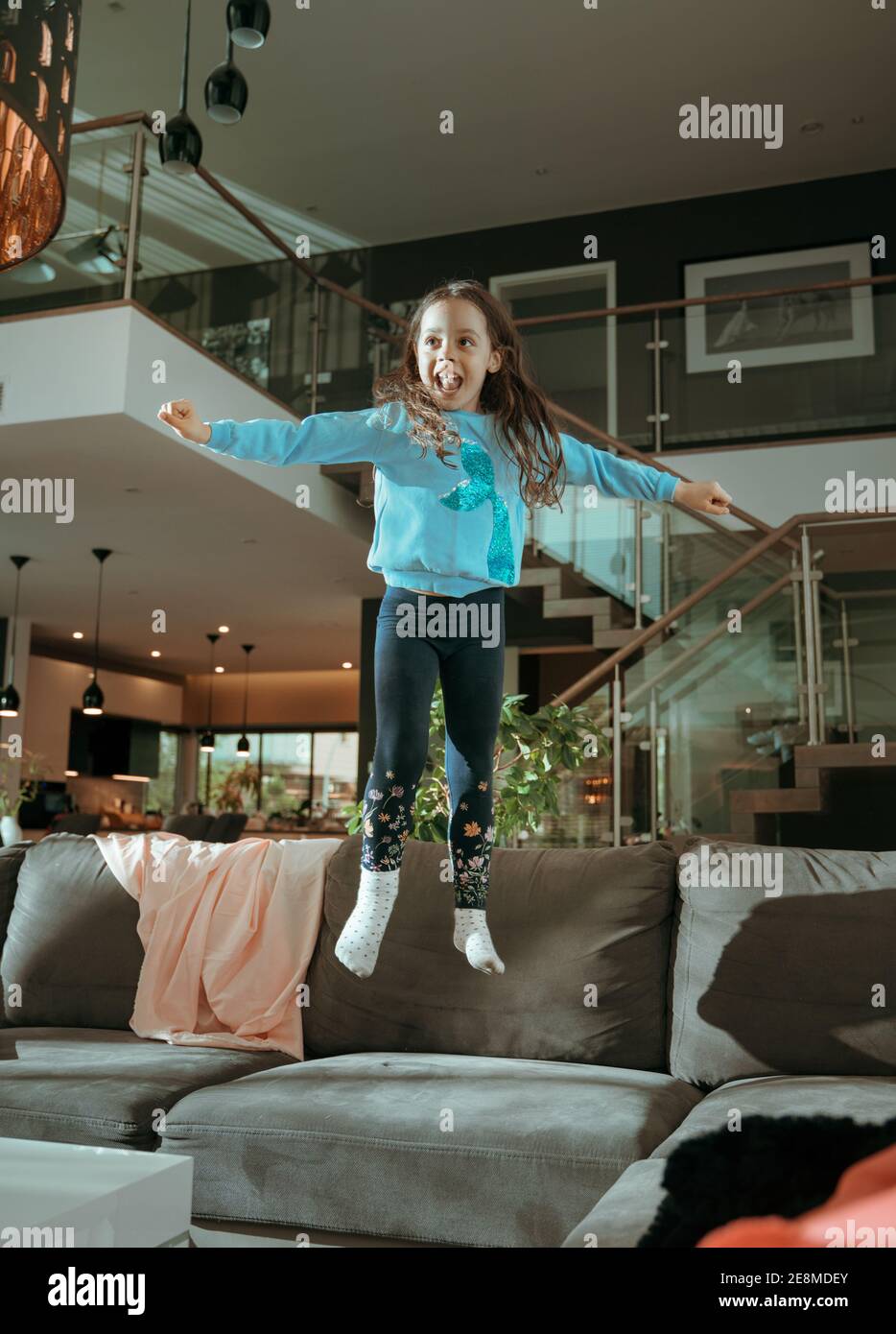 Nette, fröhliche Mädchen springen auf te Couch Stockfoto