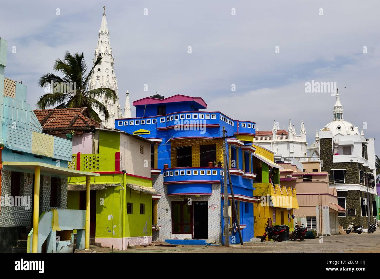 Kanyakumari, Tamil Nadu, Indien - Januar, 2017: Bunte Häuser von Fischern und ein Teil der alten Kolonialkirche am Meer in der Nähe des Meeres Stockfoto
