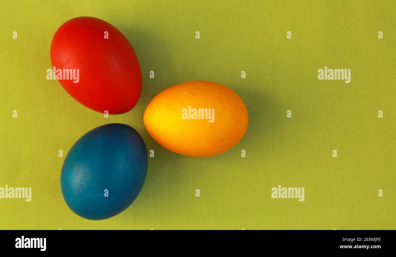 Rund rot, gelb und blau gefärbte Ostereier auf lebhaft grünem Hintergrund 2020 Konzept. Das Malen von Eiern ist eine christliche Tradition während der Osterferien al Stockfoto
