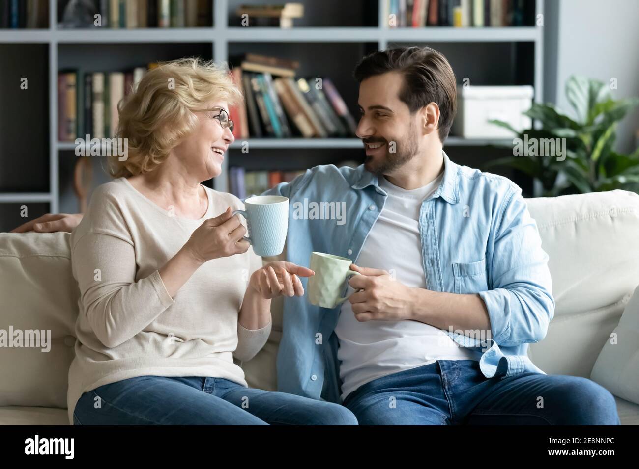 Lächelnd angenehme ältere Mutter mittleren Alters, die mit erwachsenem Sohn plaudert. Stockfoto