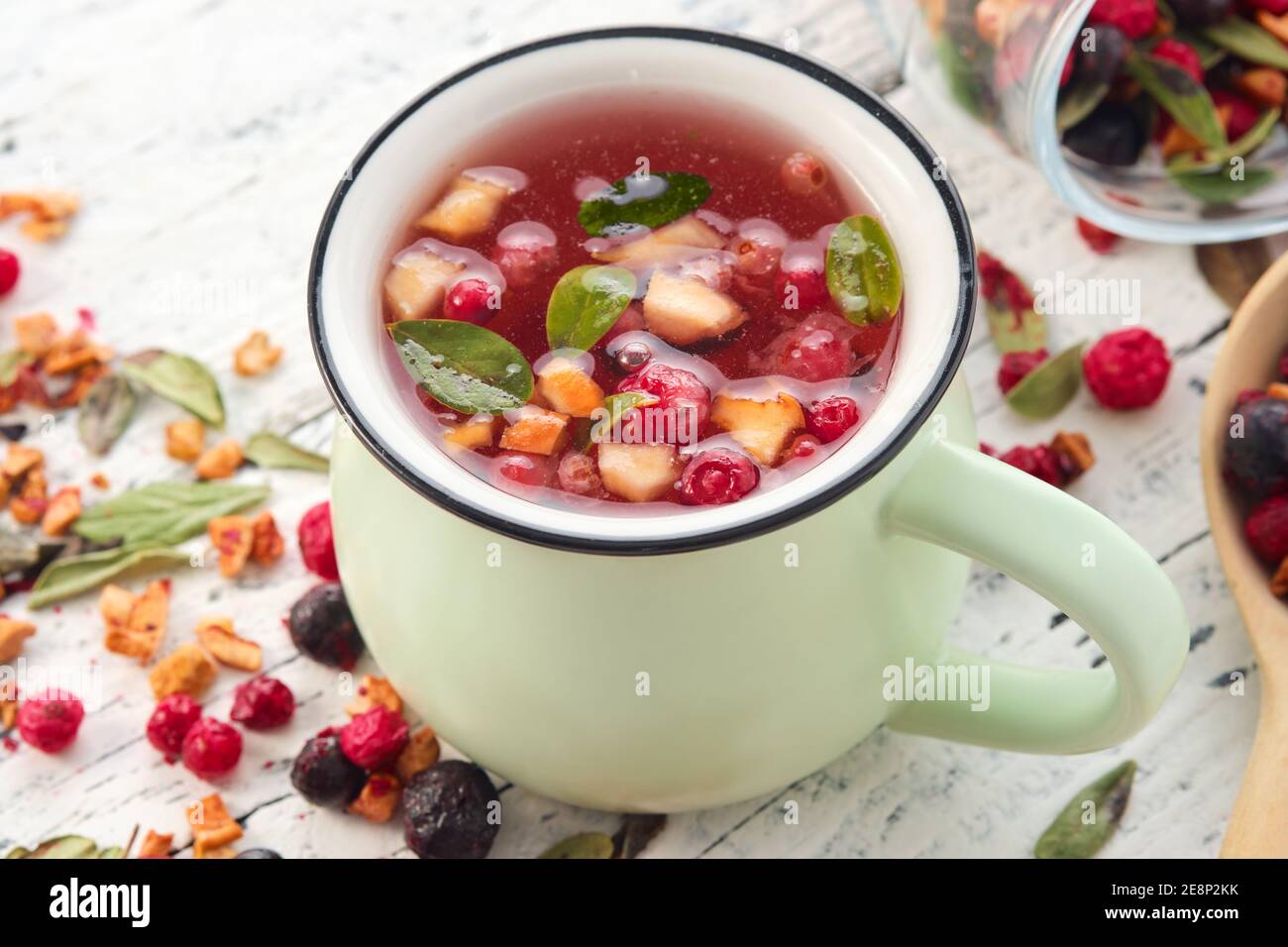 Grüne Tasse gesunden Früchtetee mit Äpfeln, Orange, Rot und Schwarz Johannisbeeren. Stockfoto