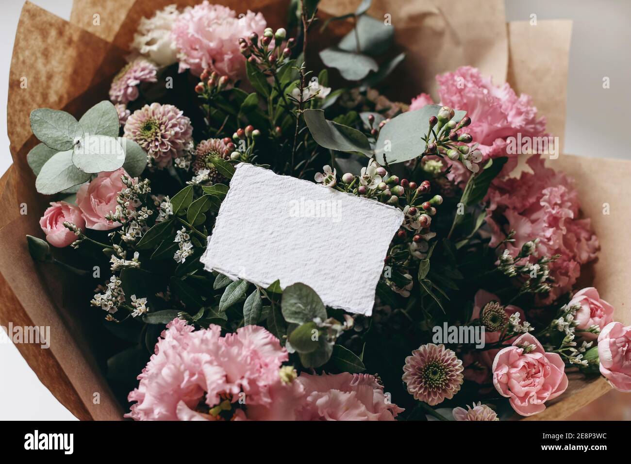 Moody feminine Hochzeit, Geburtstag Mockup Szene. Nahaufnahme von leerem Baumwollpapier Karte, Einladung auf rosa Blumenstrauß. Eustoma, santini Mütter und Stockfoto