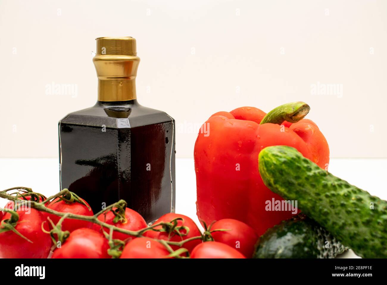 Auf weißem Hintergrund ist eine quadratische Flasche Wein und frisches Gemüse. Stockfoto