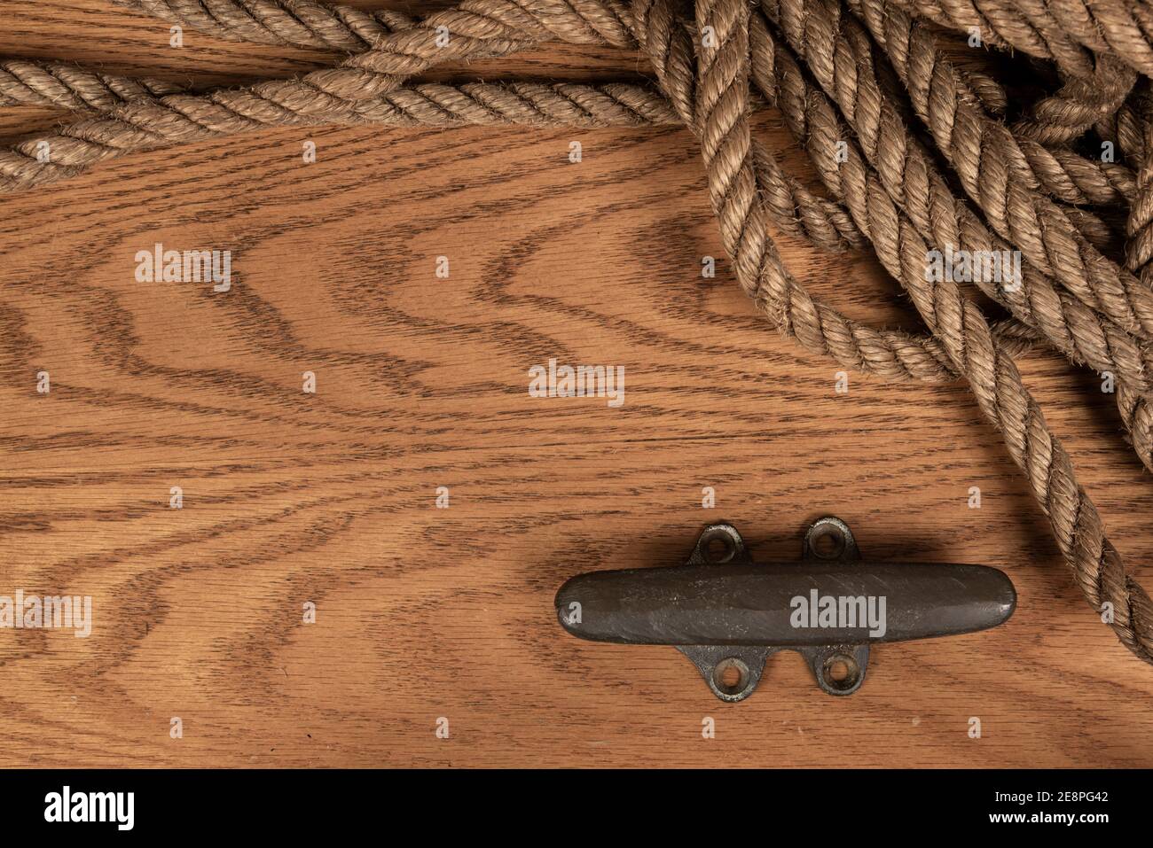 Hintergrund mit Seil und einem Strang auf einem Holzbrett mit Platz für Text auf der linken Seite. Sättigung wurde reduziert. Stockfoto
