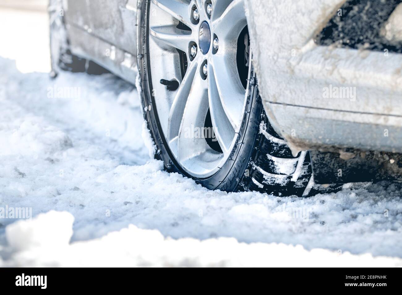 Nahaufnahme von PKW-Reifen im Winter auf der Straße mit Schnee bedeckt. Stockfoto