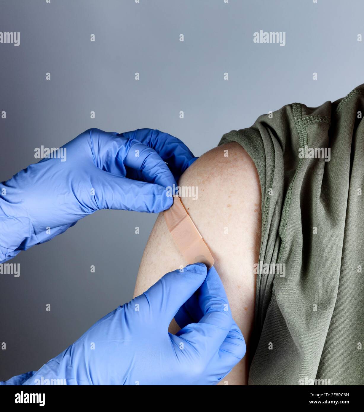 Medizinische Arbeiter setzen Band Hilfe auf männlichen Oberarm nach Coronavirus-Impfstoff erschossen Stockfoto