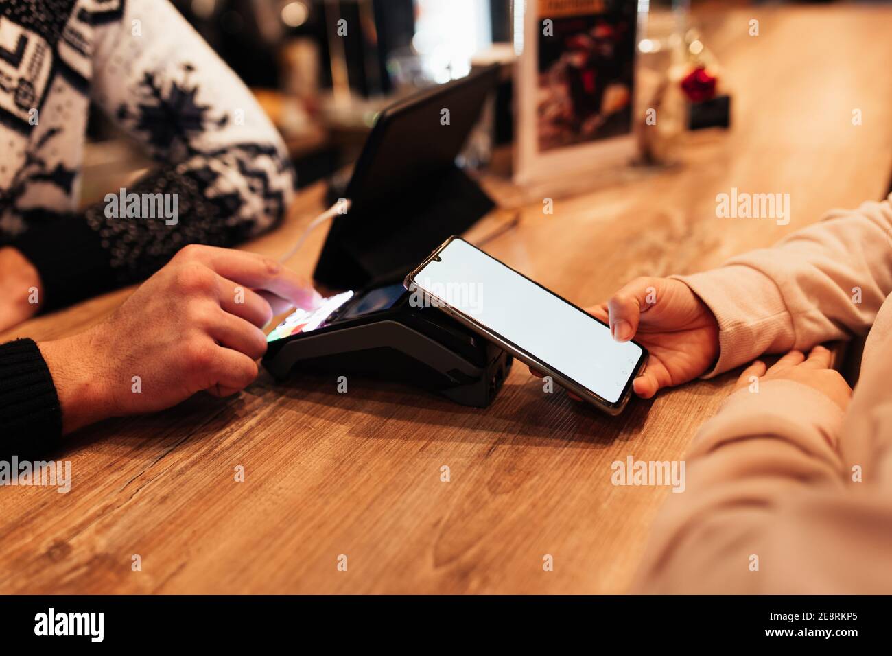 Bargeldloses Bezahlen mit NFC und Telefon in einem Café-Terminal. Unscharfer Hintergrund Stockfoto