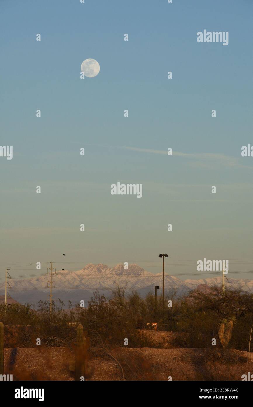 Mond über dem Schneedeckenberg in Phoenix, Arizona, USA bei Sonnenuntergang nach seltenem Wetter Wintersturm. Stockfoto